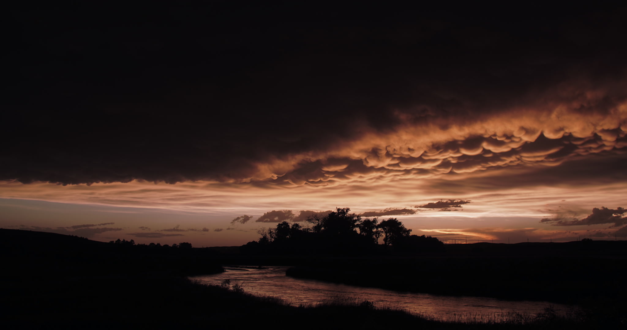 Storm clouds - Orange mammatus clouds drift over Middle Loup River, Nebraska at sunset, time-lapse, 4K. Cinematographer: Martin Lisius. Need more cinematic-quality storm shots? Please contact us.