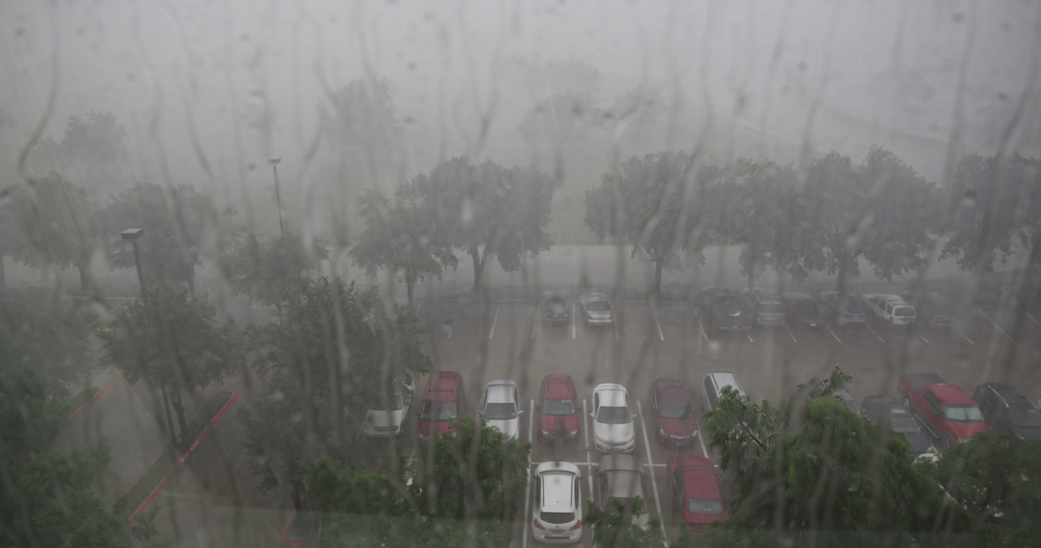 Rain storm - Rain drops on window, cars, parking lot below, 4K.