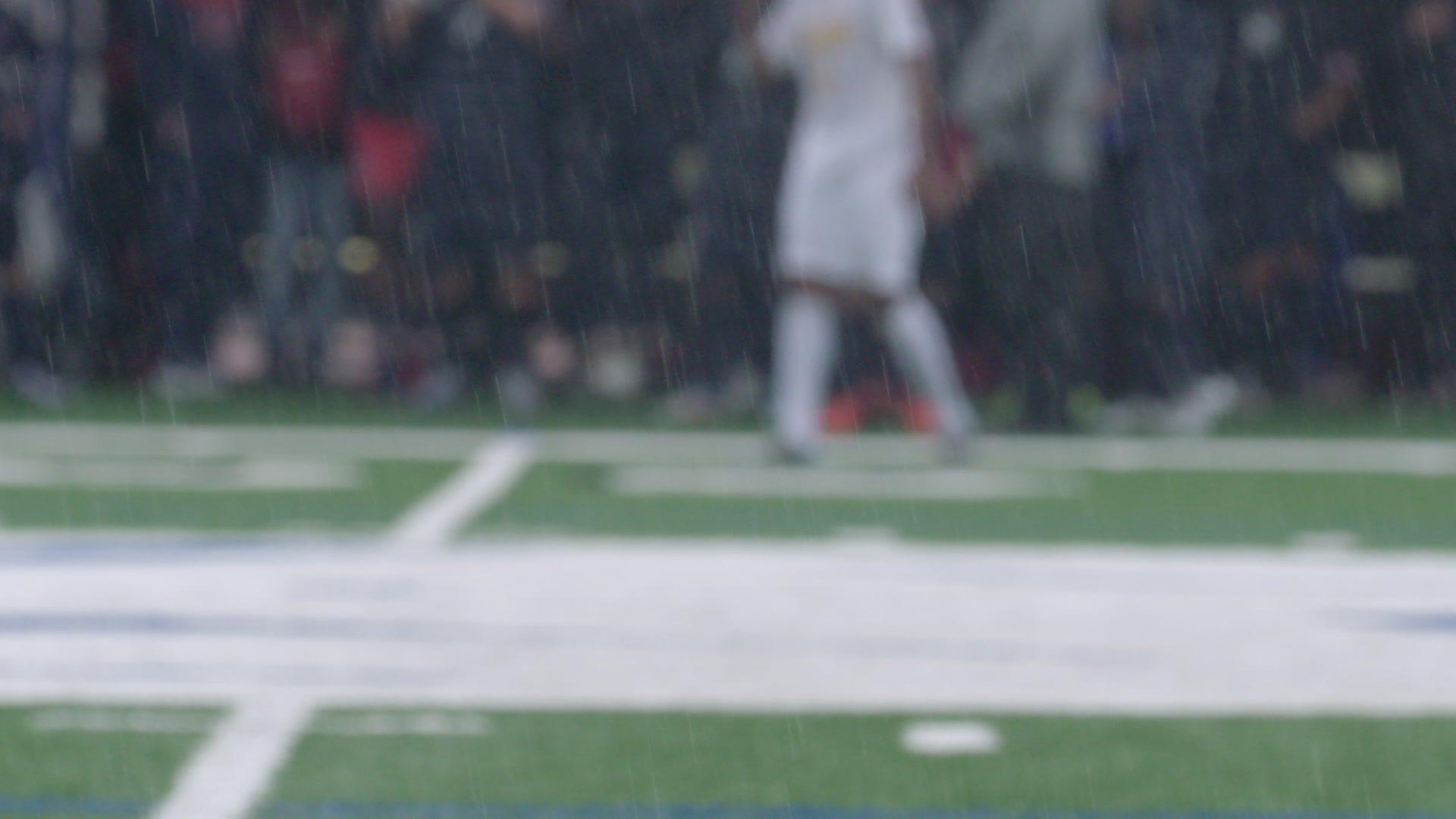 Rain falls during soccer game, slow-motion, close-up, 4K.