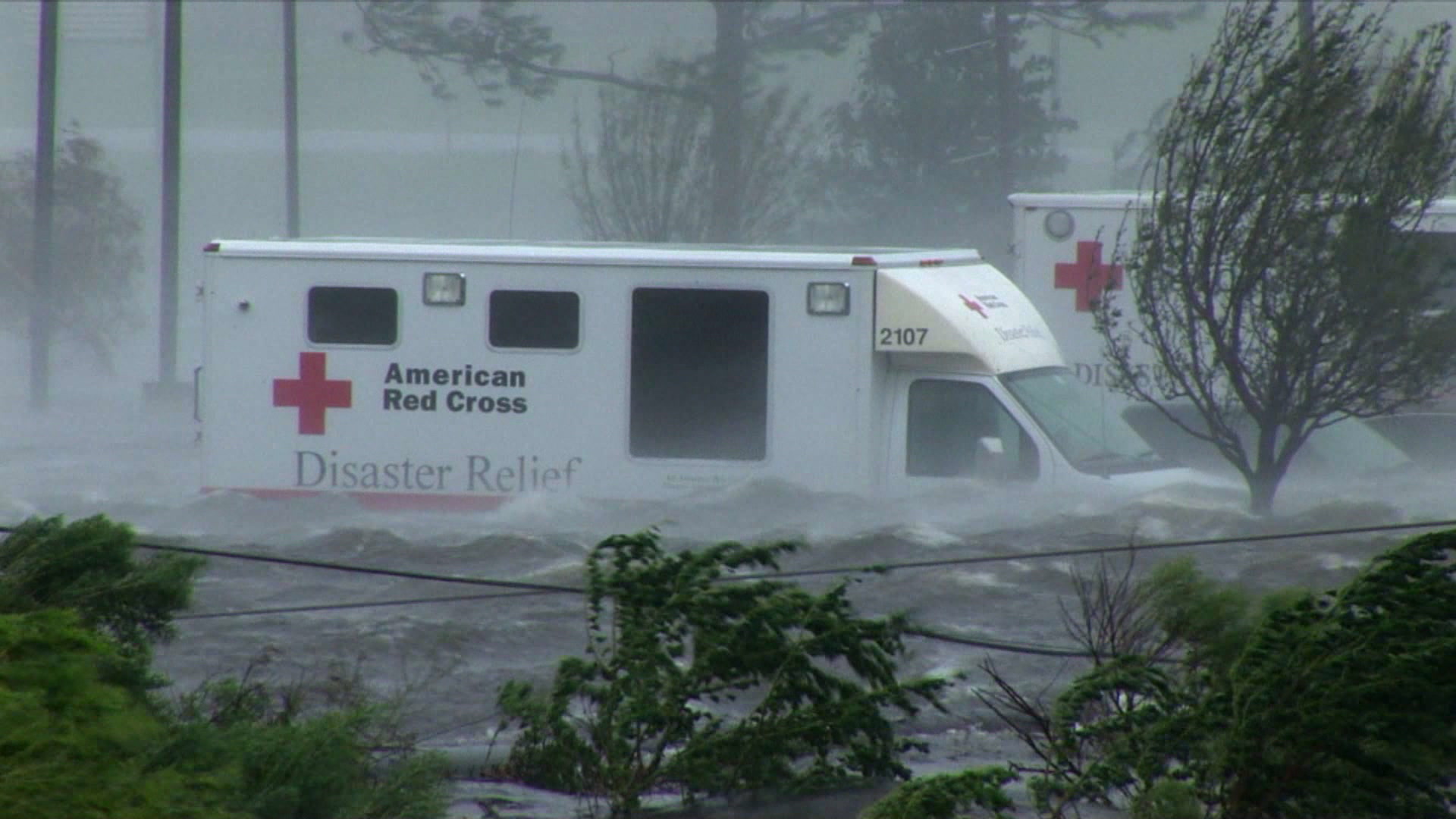 Dramatic shot of Red Cross Disaster Relief truck caught in storm surge, high winds, Hurricane Katrina, 4K video. Cinematographer: Martin Lisius.