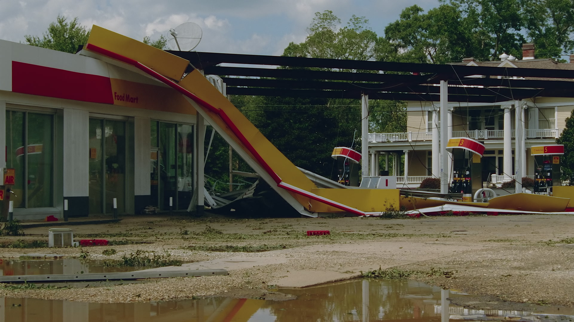 Wide shot of damaged gas station and house, Hurricane Katrina, 35mm film to 4K video. Cinematographer: Martin Lisius.