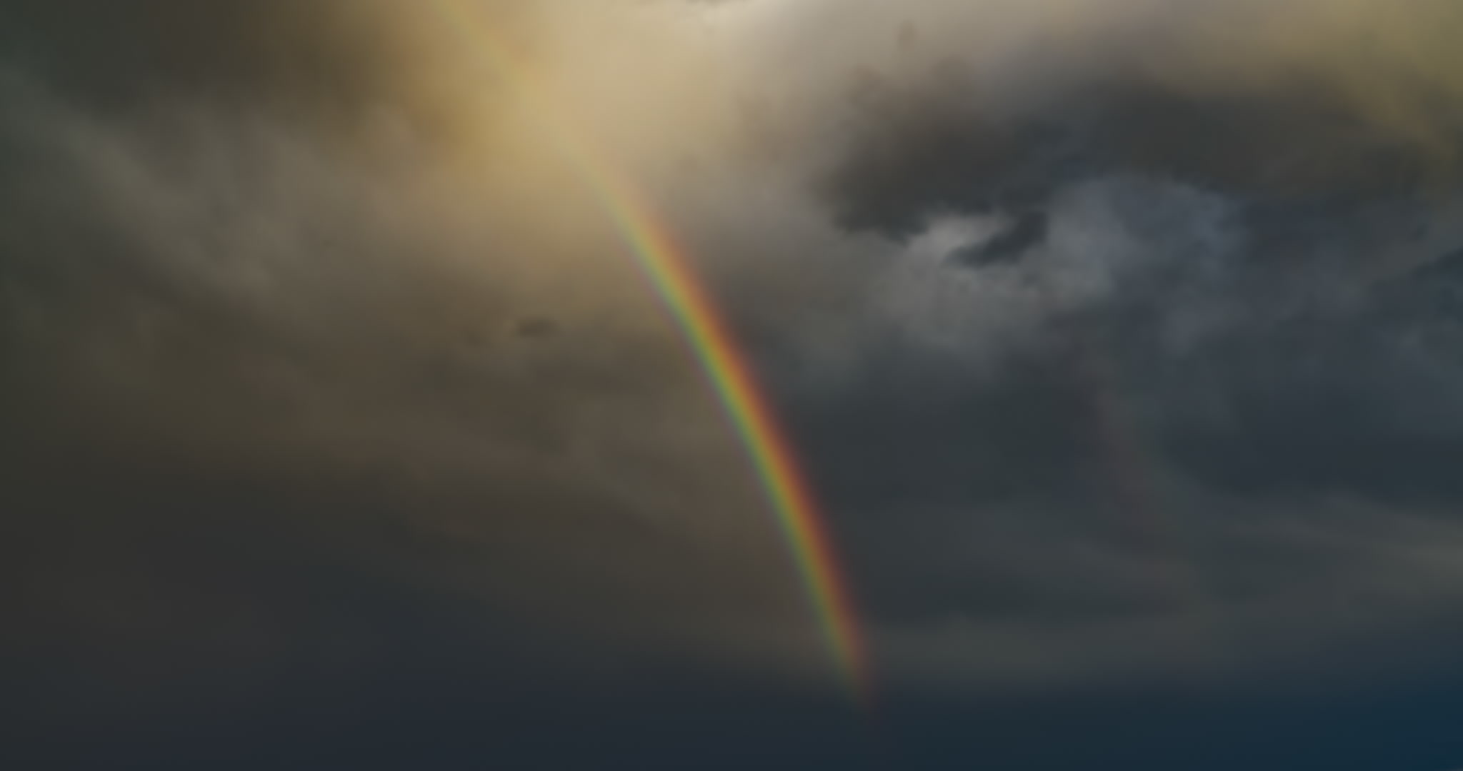 Rainbow segment against dark, stormy sky, close-up, time-lapse. DCI 4K.