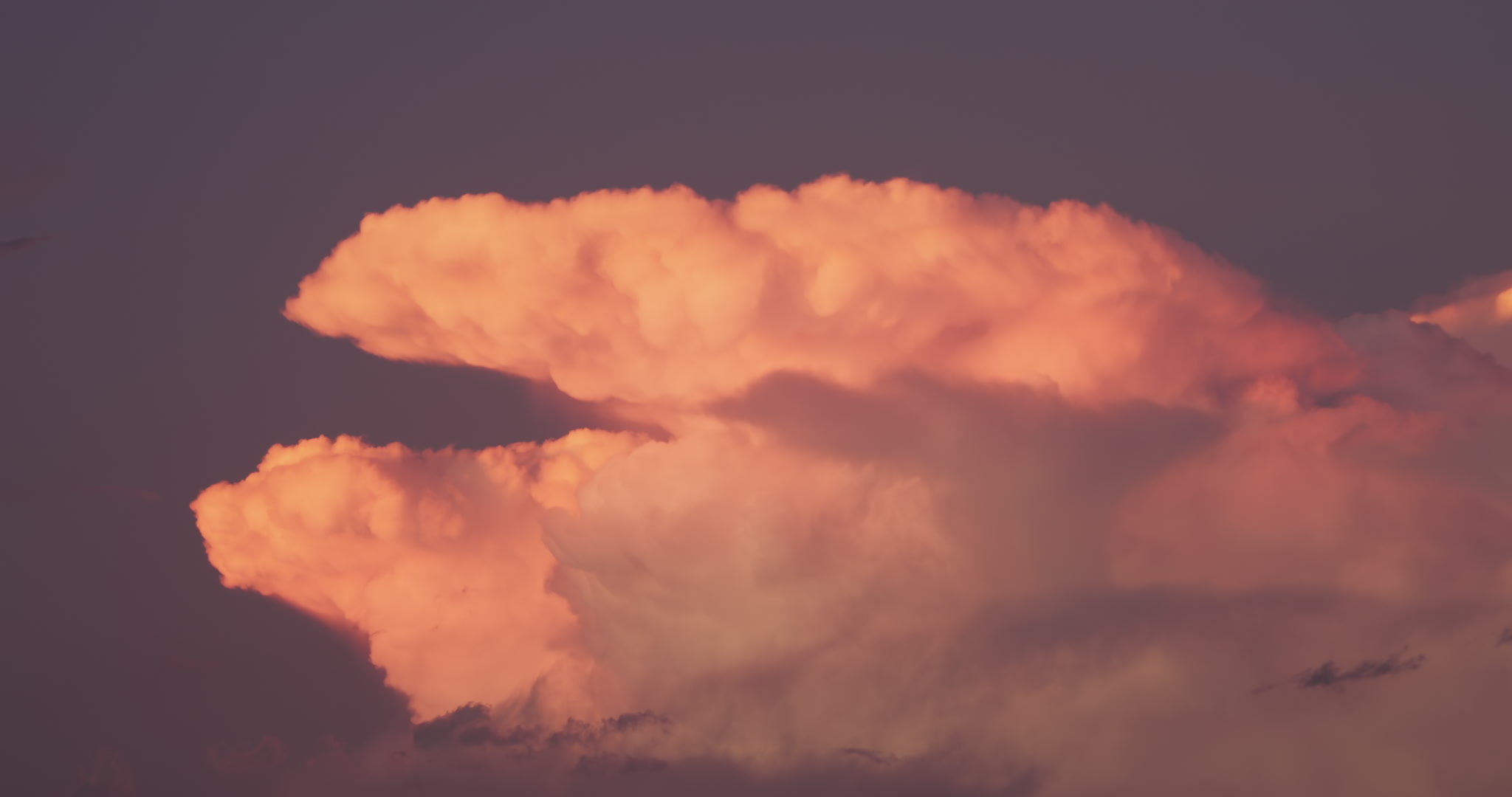Top of storm is colored pink and orange by setting sun. DCI 4K.