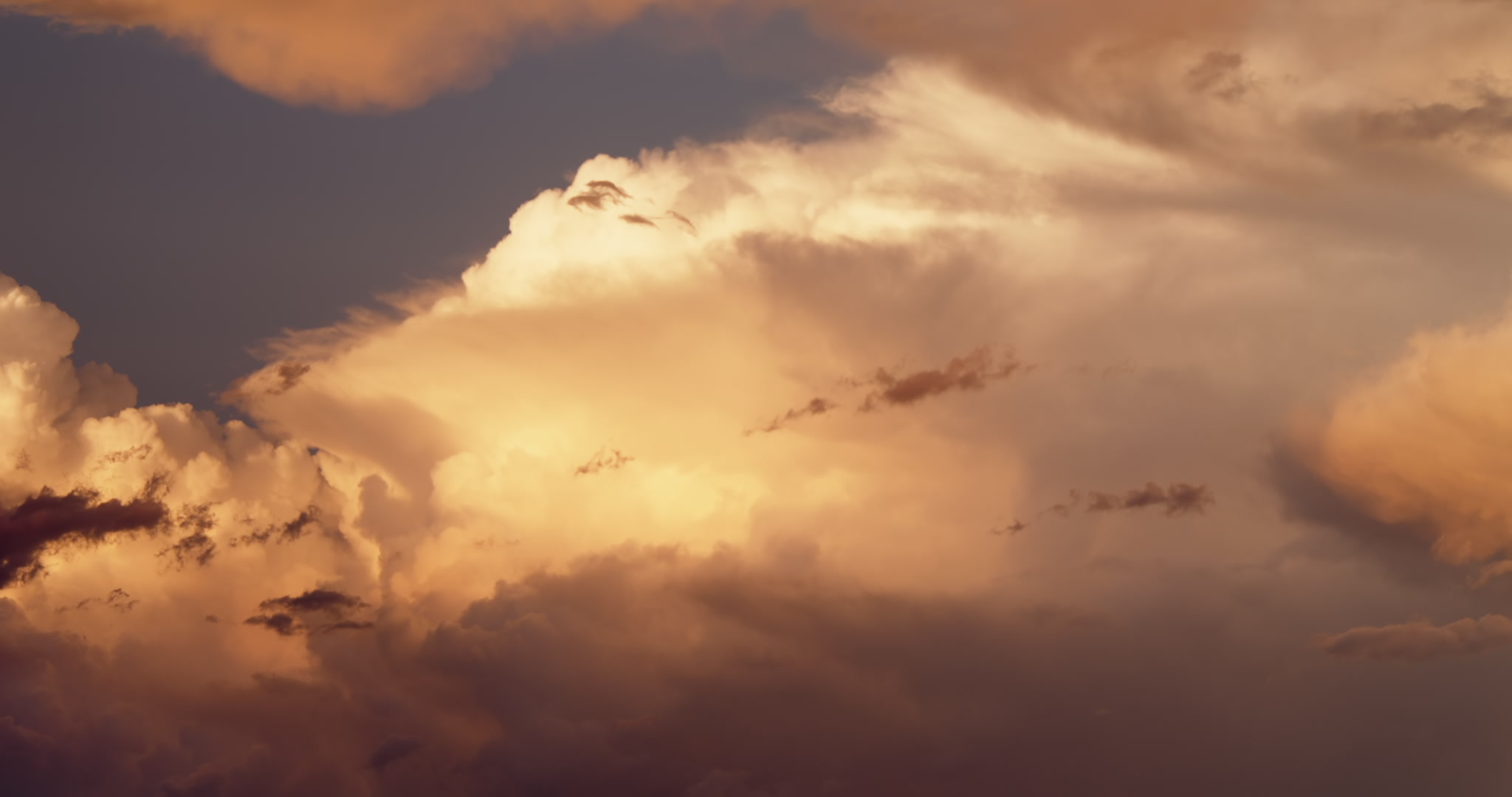 Tall, severe storm lit orange by setting sun. DCI 4K.