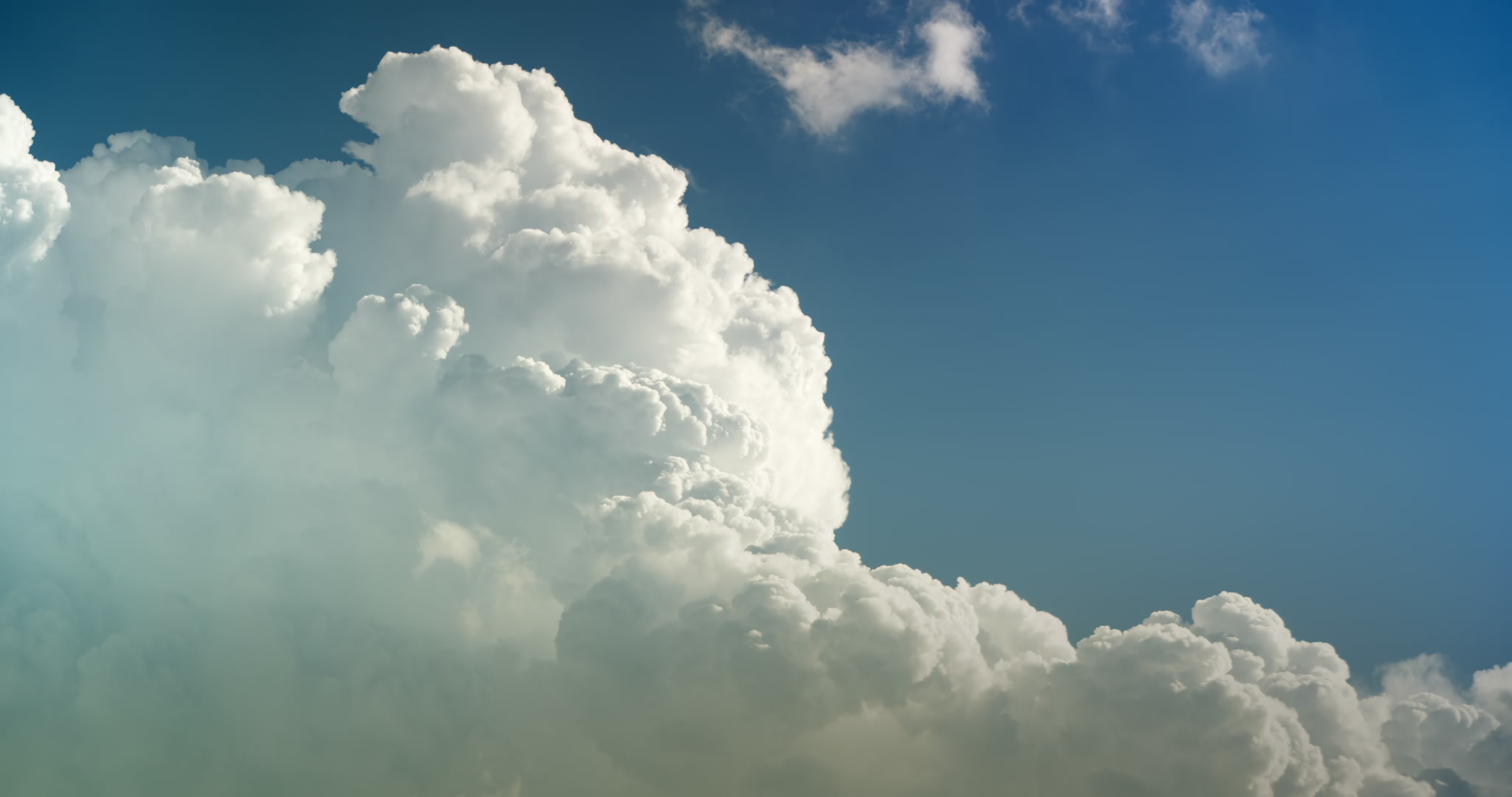 Tall, towering cumulus cloud builds upward into blue sky. Real-time. DCI 4K.