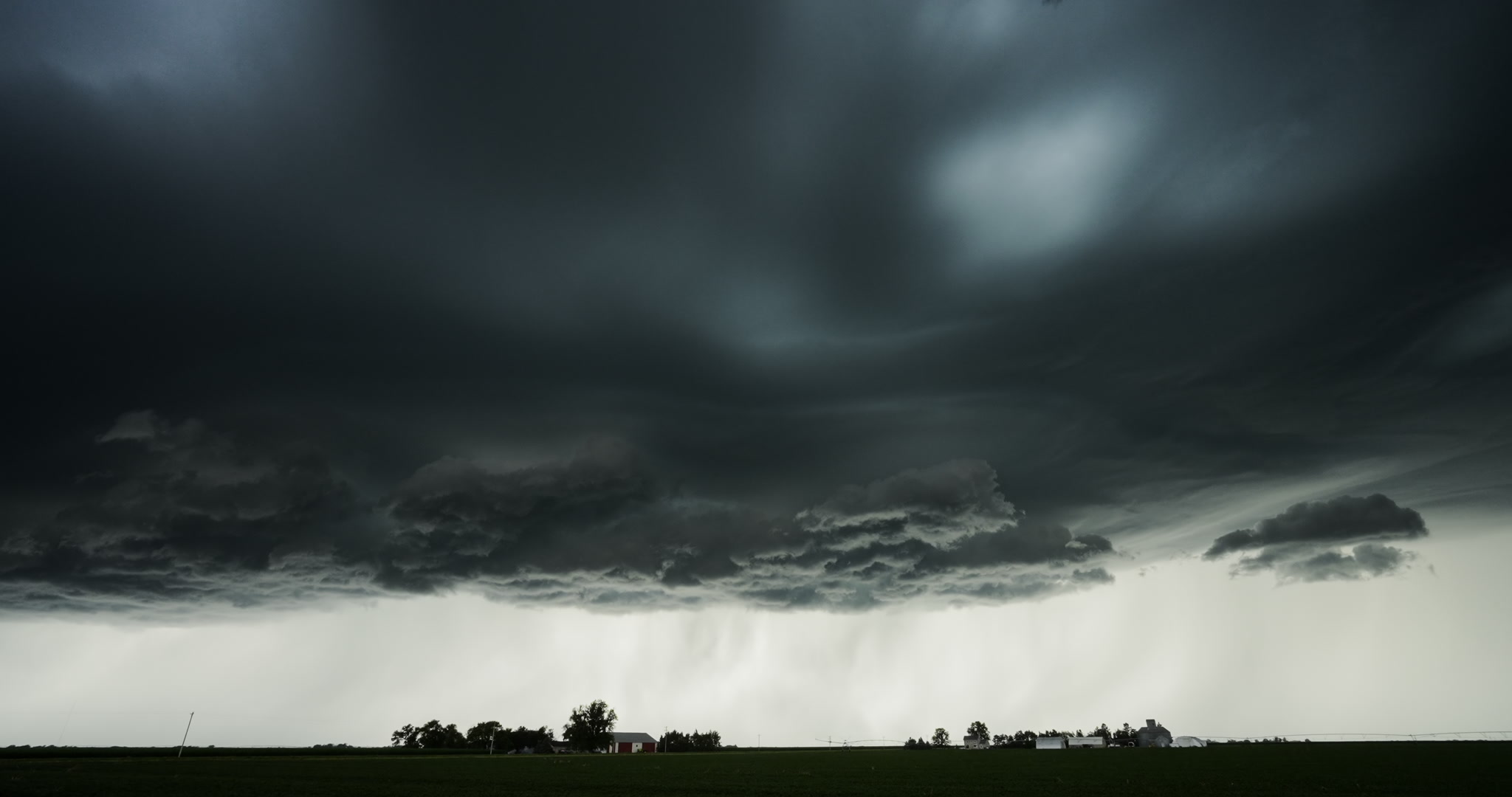 Real-time shot, alien like storm with lightning bolt passes over two farms. DCI 4K.