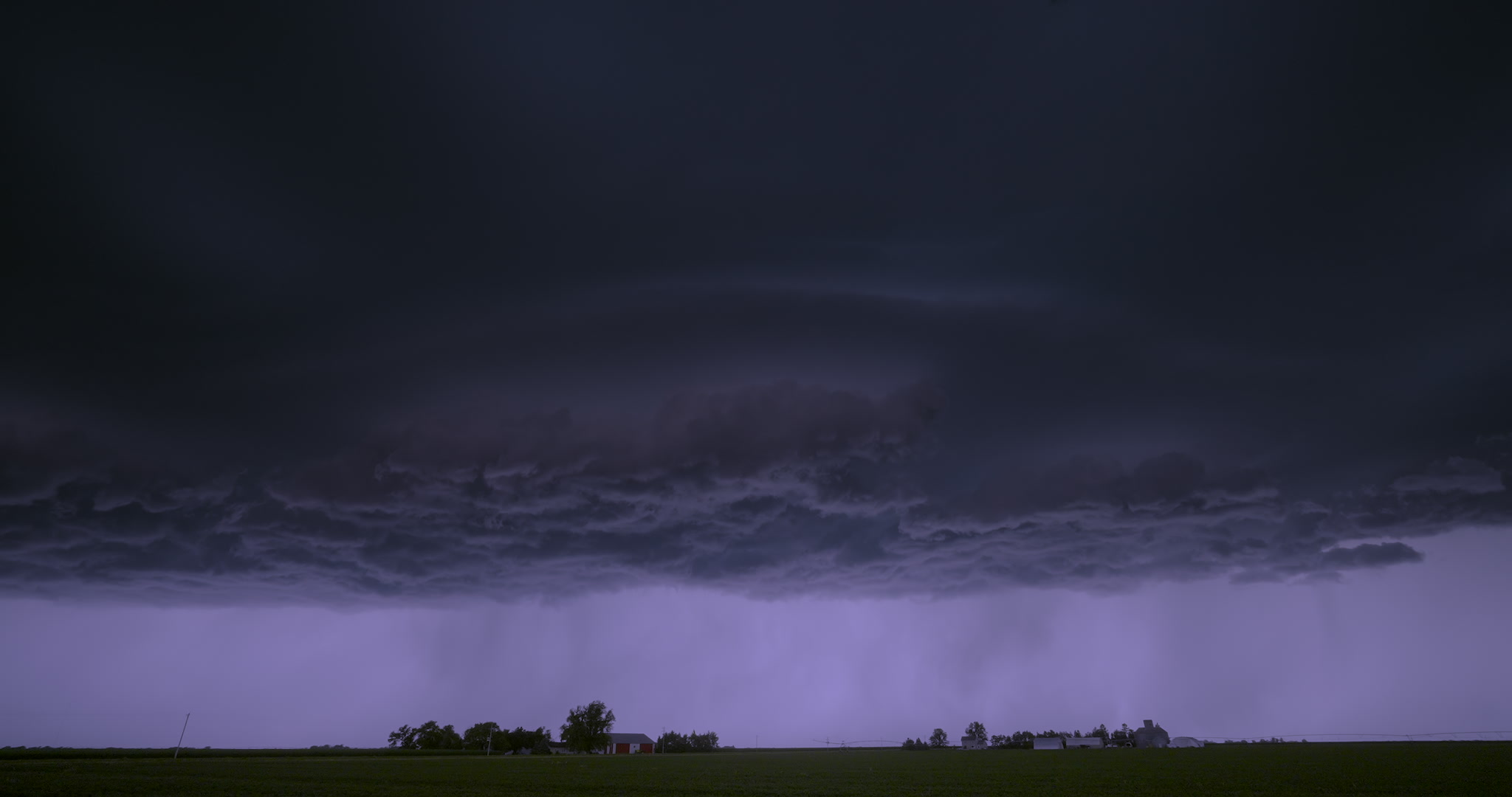 Night view of alien-like storm drifting over two farms, 4K. DCI 4K.