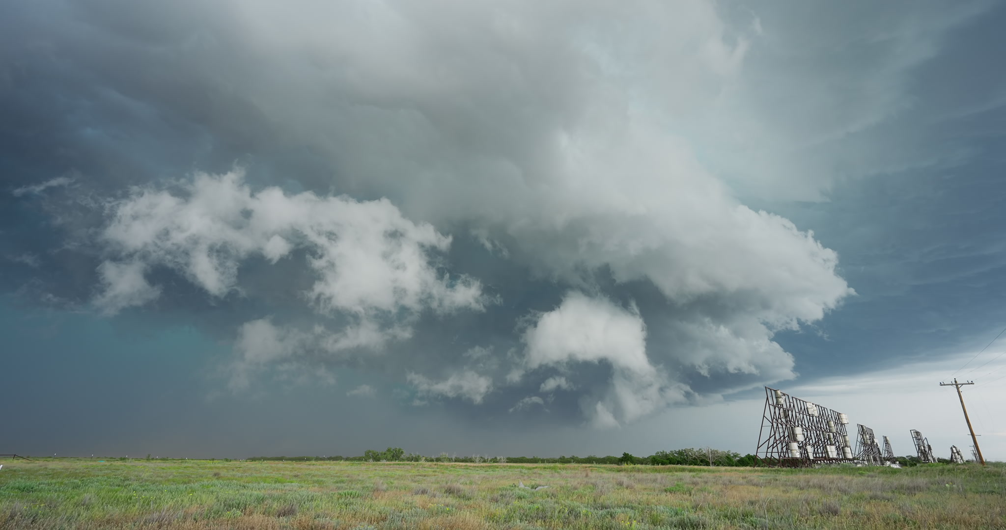 Large severe storm drifts over prairie and wind machines. DCI 4K.