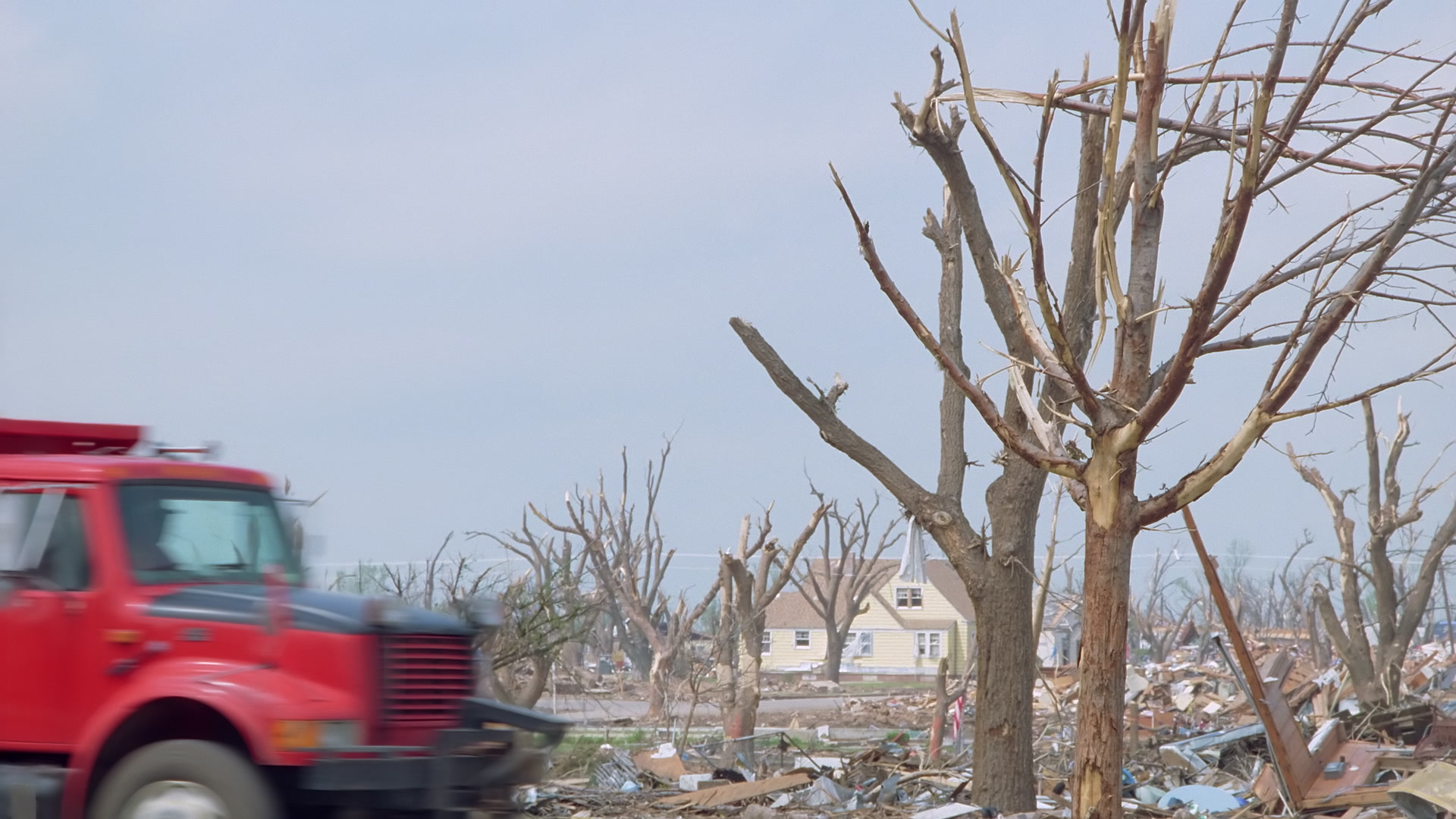 Tornado damage and aftermath - red debris truck goes by, stripped trees, Greensburg EF5 aftermath, 35mm film to 4K.