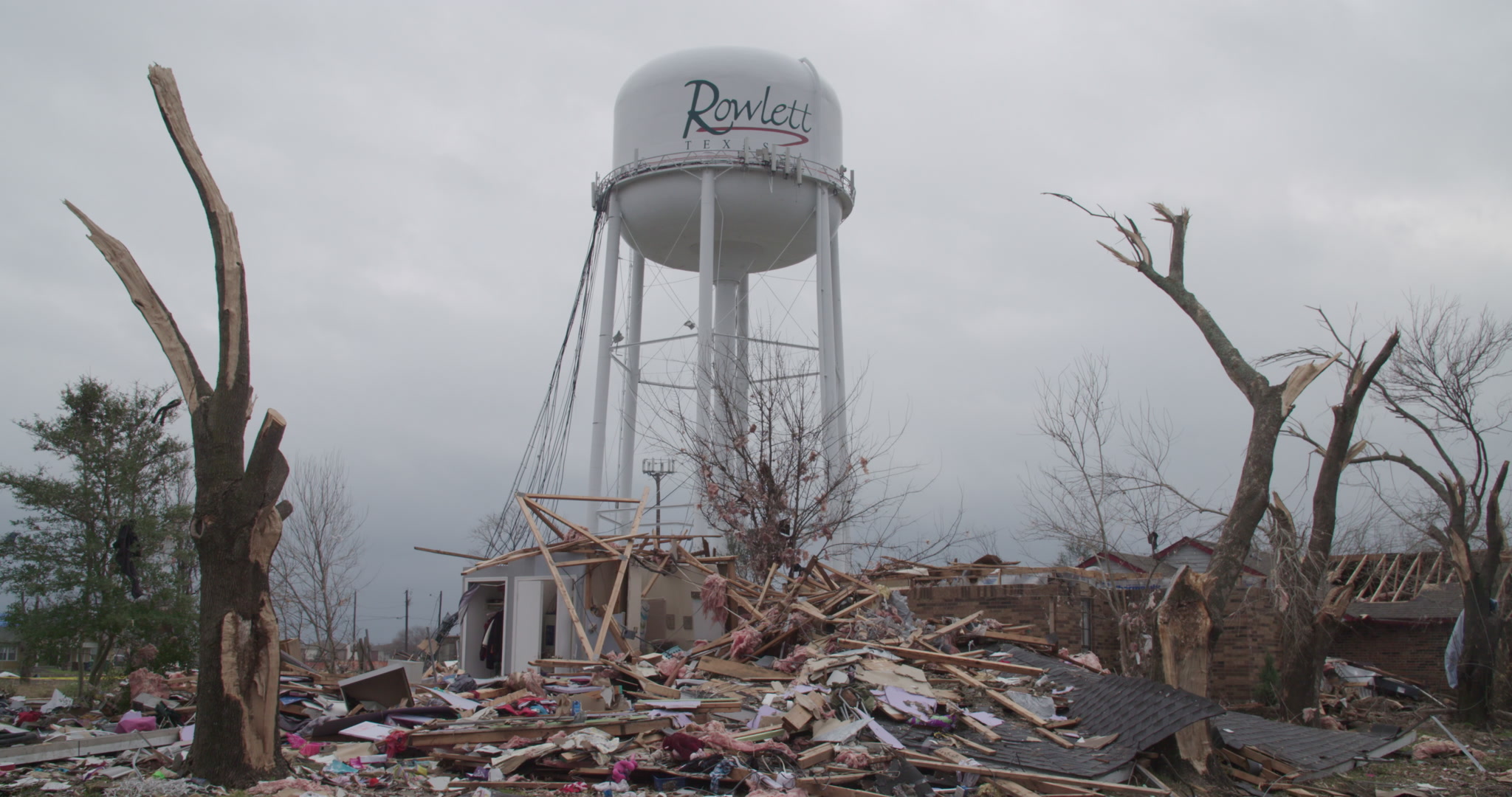 Tornado damage and aftermath - Pan up over debris to reveal Rowlett, Texas water tower, 4K.