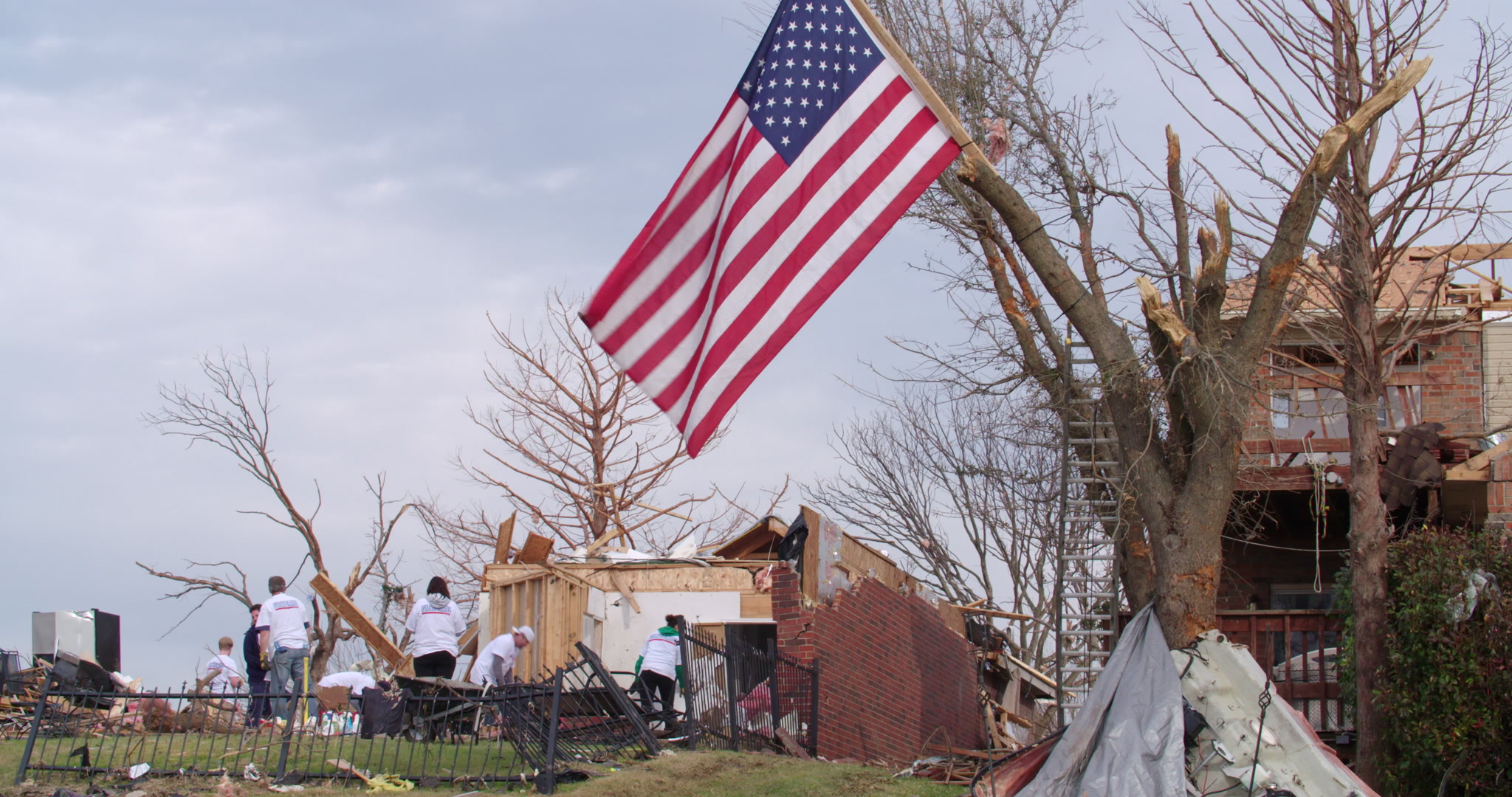 Tornado damage and aftermath - American flag over damaged area, cleanup, 4K.