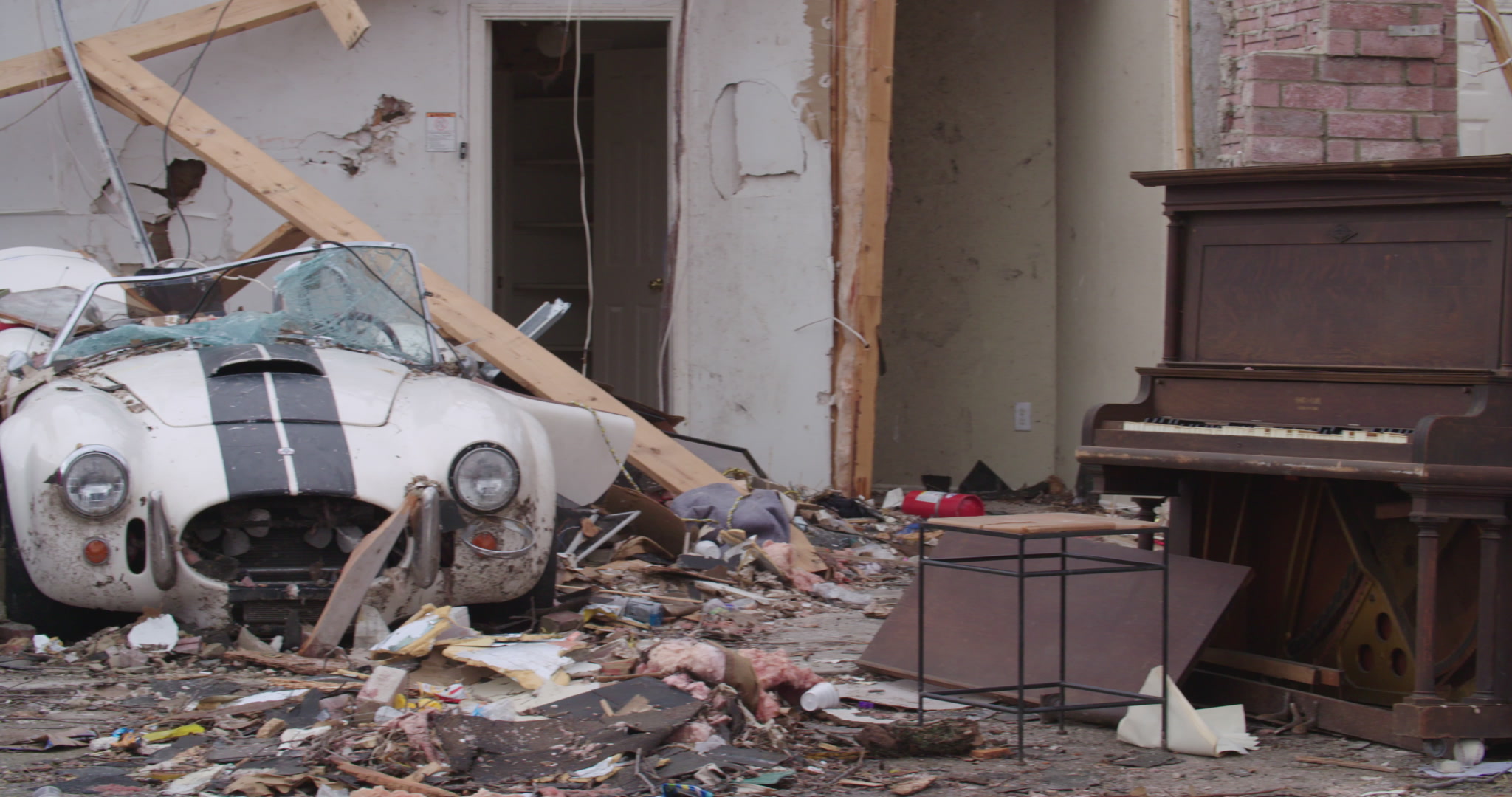 Tornado damage and aftermath - pan left, piano and two sports cars, 4K.