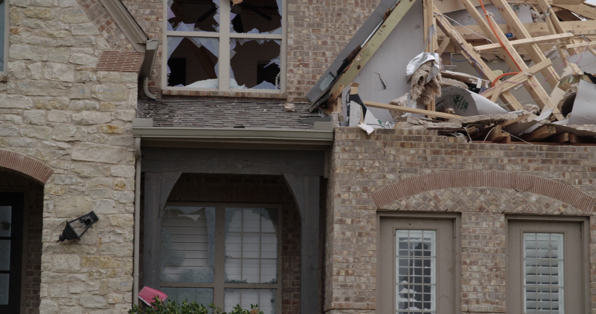 Tornado damage and aftermath - pan left, damaged brick and stone house, 4K.