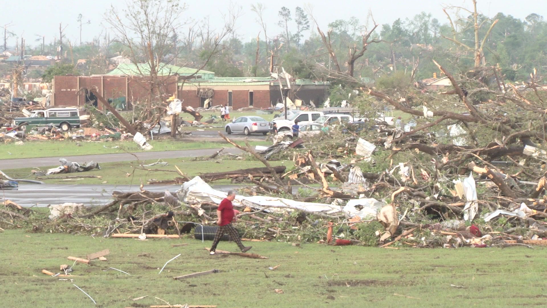 Tornado damage and aftermath - man in pajama pants walks across destroyed neighborhood.