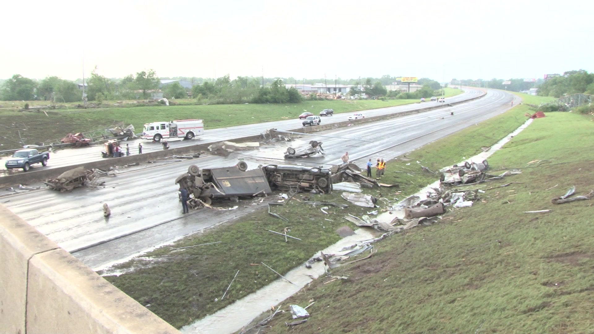 Tornado damage and aftermath - Delivery truck, cars strewn across highway, first responders arrive.