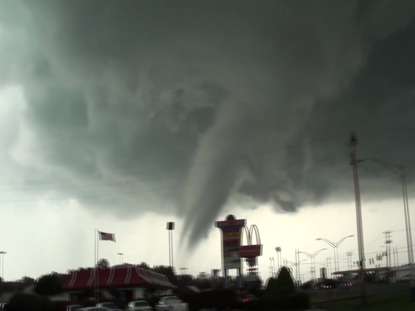 Tornado - destructive tornado in city passes behinds McDonalds sign.