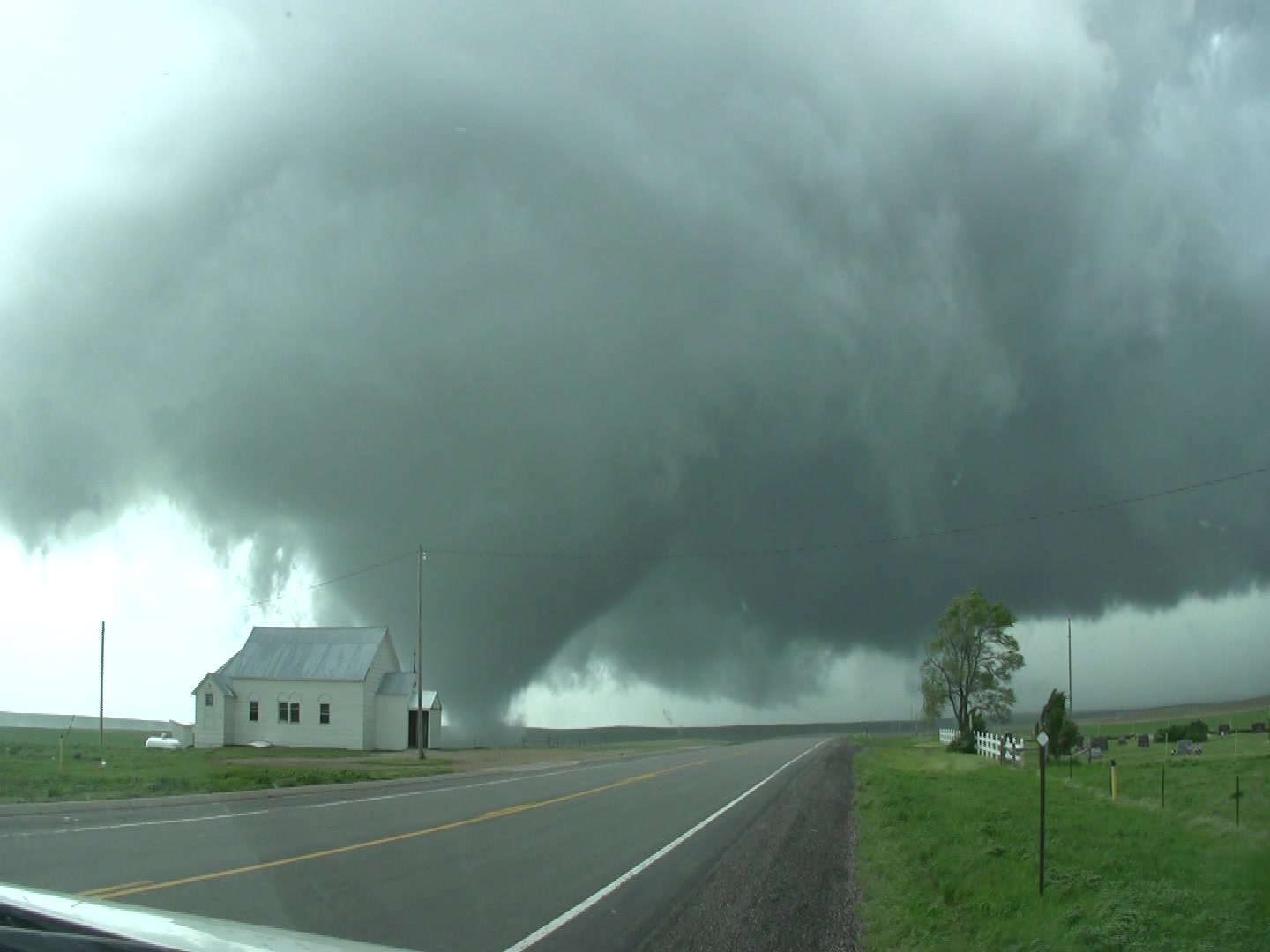 Tornado - Cone shaped tornado tracks behind white church and over rural highway, South Dakota.